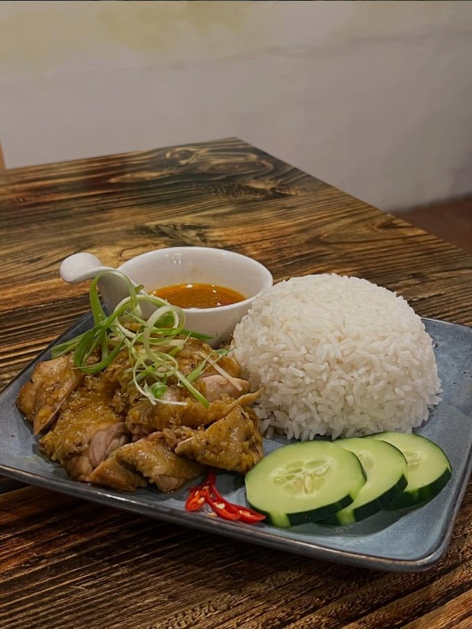Sliced chicken with a mound of white rice, cucumber slices and chili on a blue plate