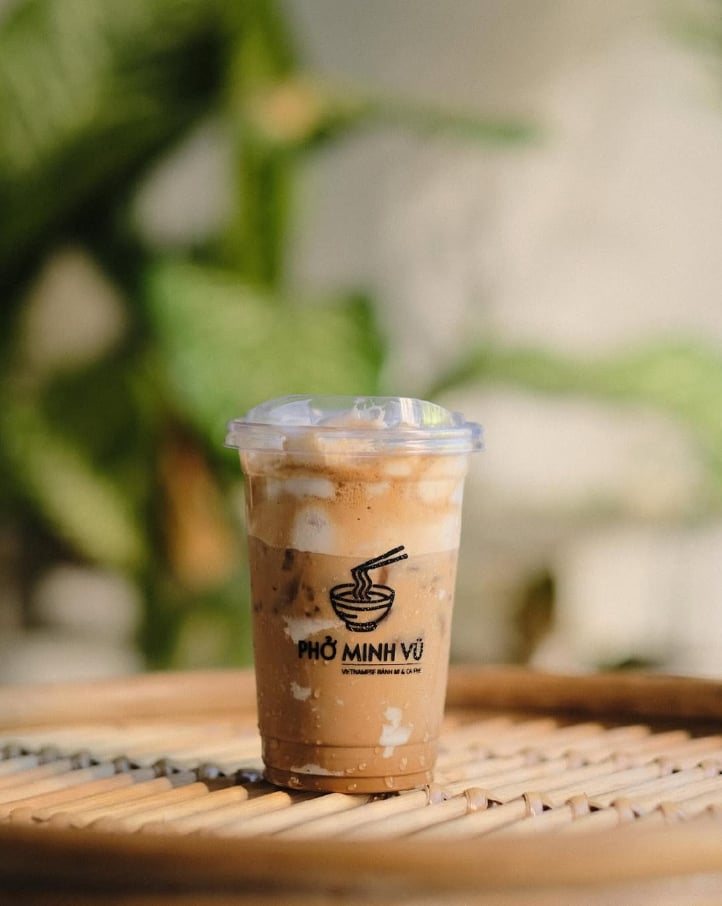 Iced coffee in a Phở Minh Vũ cup on a rattan tray