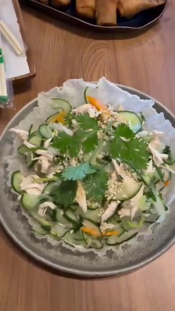 Chicken salad with cucumber, herbs and sesame on a grey plate